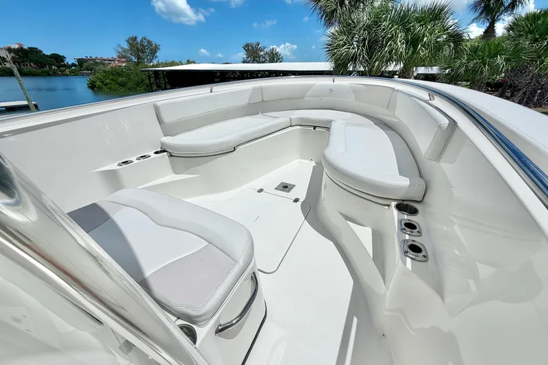 Slide: The Image of 2013 Edgewater 318CC boat interior with white seating and cup holders, surrounded by lush greenery. - 3