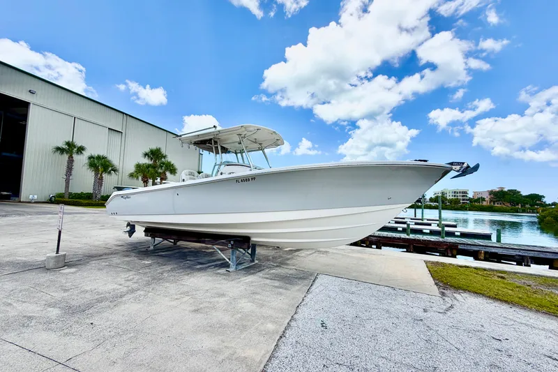 Slide: The Image of 2013 Edgewater 318CC boat on trailer near waterfront, under a clear blue sky. - 4