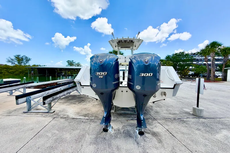 Slide: The Image of 2013 Edgewater 318CC boat with twin Yamaha 300 V6 engines, docked under a clear sky. - 8