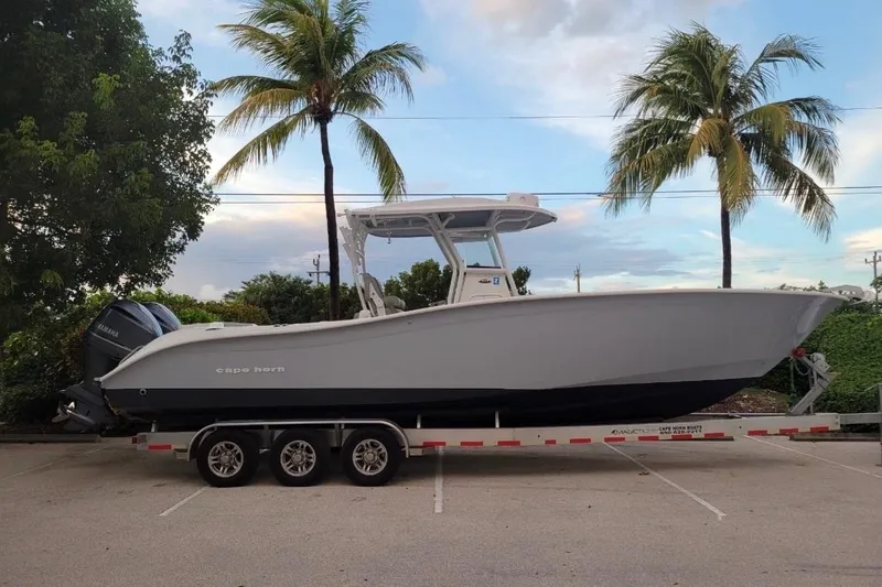 The Image of 2021 Cape Horn 32 XS boat on trailer, parked near palm trees. - 0
