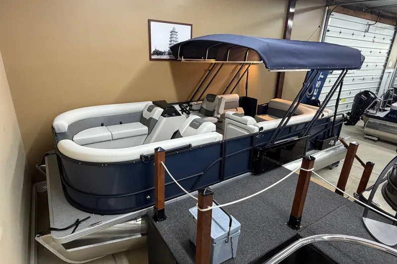 The Image of 2026 Crest Conquest SE 220 Cruise pontoon boat with blue canopy in showroom. - 1