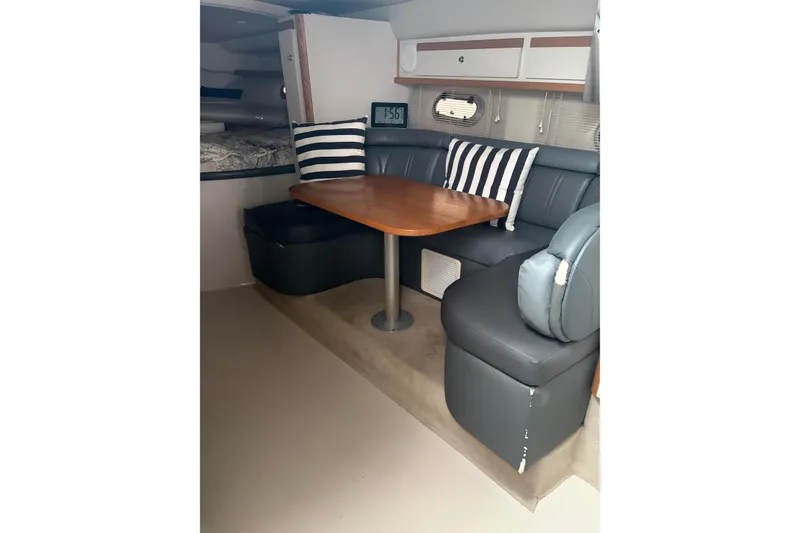 Slide: The Image of 1999 Four Winns 328 Vista cabin interior with dining area, striped cushions, and wooden table. - 15