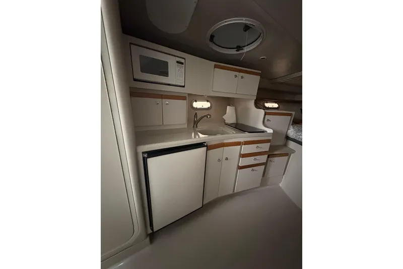 Slide: The Image of 1999 Four Winns 328 Vista boat interior kitchen with microwave, sink, and storage cabinets. - 21
