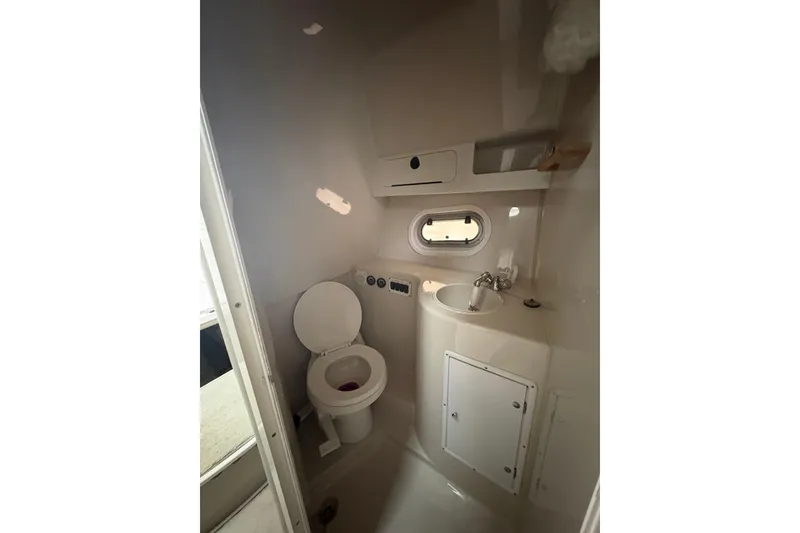 Slide: The Image of 1999 Four Winns 328 Vista boat bathroom with toilet, sink, and storage cabinet. - 34