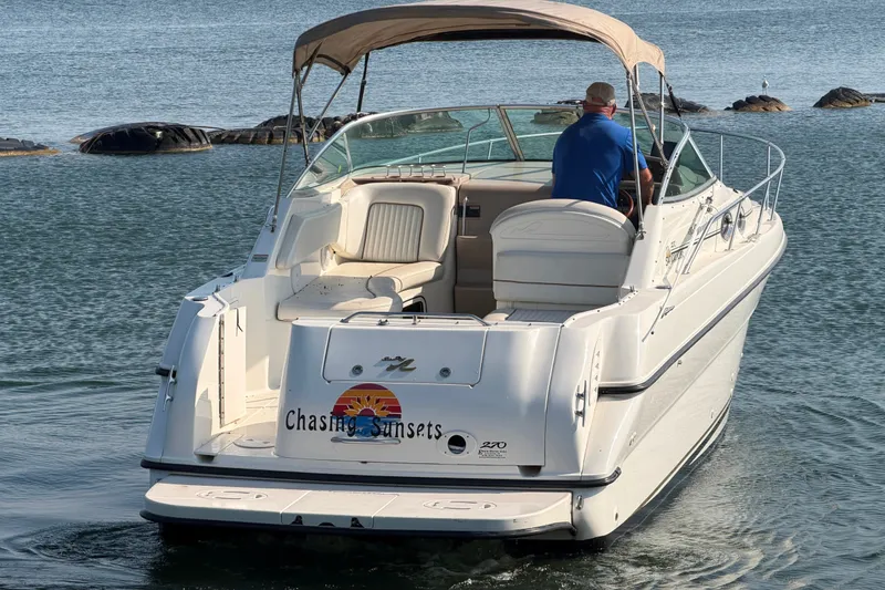 Slide: The Image of 2000 Sea Ray 270 Sundancer boat on water, rear view with canopy and "Chasing Sunsets" text. - 2