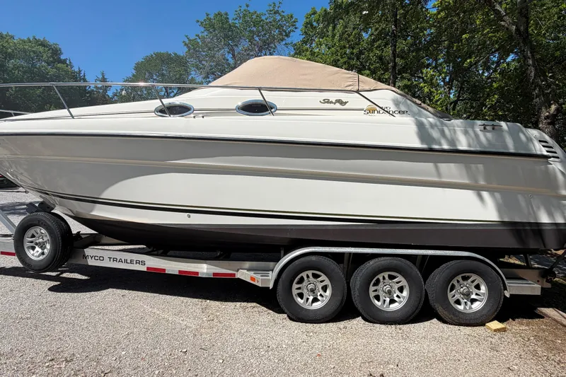 Slide: The Image of 2000 Sea Ray 270 Sundancer boat on trailer, parked outdoors with trees in background. - 14