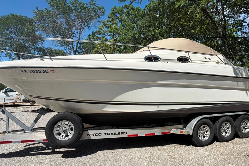 Slide: The Image of 2000 Sea Ray 270 Sundancer boat on trailer, parked outdoors with trees in background. - 13