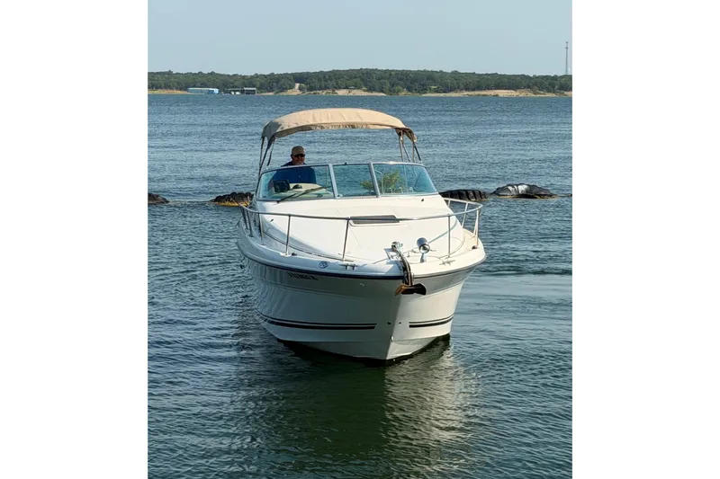 Slide: The Image of 2000 Sea Ray 270 Sundancer boat cruising on a calm lake with scenic background. - 7