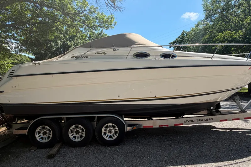 Slide: The Image of 2000 Sea Ray 270 Sundancer boat on trailer, parked outdoors under trees. - 11