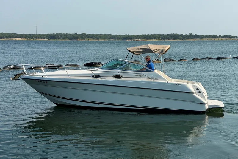 Slide: The Image of 2000 Sea Ray 270 Sundancer boat cruising on a calm lake with a scenic shoreline. - 5