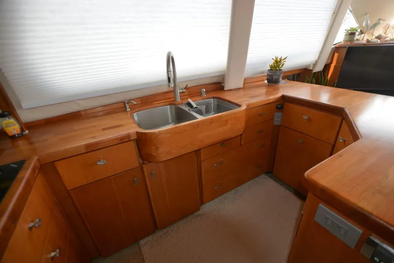 Slide: The Image of Interior of 2000 Carver 504 Cockpit Motor Yacht kitchen with wooden cabinetry and stainless steel sink. - 14