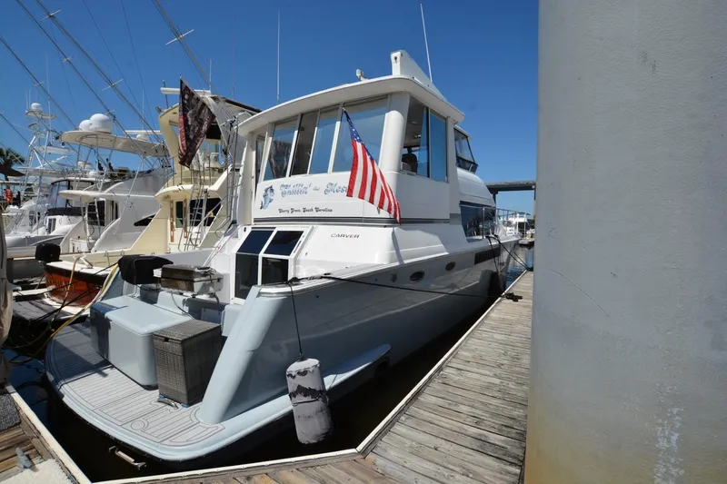Slide: The Image of 2000 Carver 504 Cockpit Motor Yacht docked at marina, displaying American flag. - 2