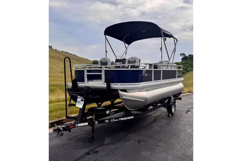 Slide: The Image of 2026 Sun Tracker Bass Buggy 18 DLX pontoon boat on trailer, parked outdoors. - 3