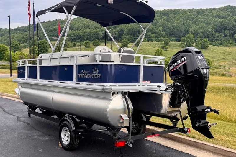 Slide: The Image of 2026 Sun Tracker Bass Buggy 18 DLX pontoon boat with Mercury engine, parked outdoors. - 83