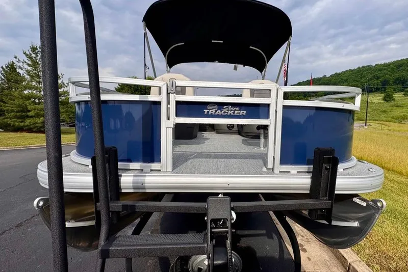 Slide: The Image of 2026 Sun Tracker Bass Buggy 18 DLX pontoon boat on trailer, scenic outdoor setting. - 4
