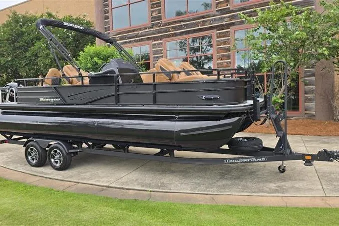 Slide: The Image of 2026 Ranger 223F pontoon boat on trailer, parked outdoors near a building. - 6