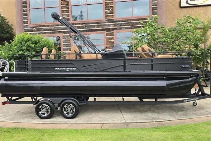 The Image of 2026 Ranger 223F pontoon boat on trailer, parked outdoors near a building. - 0