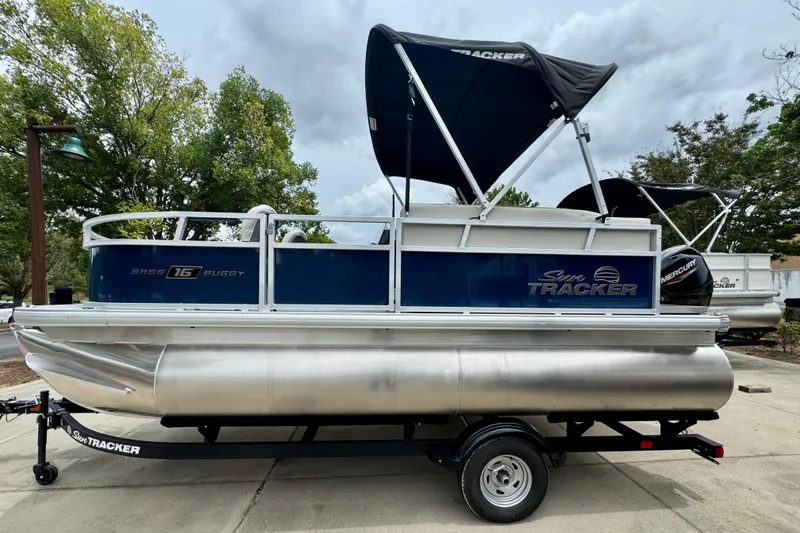The Image of 2026 Sun Tracker Bass Buggy 16 XL Select pontoon boat on trailer, outdoors. - 0
