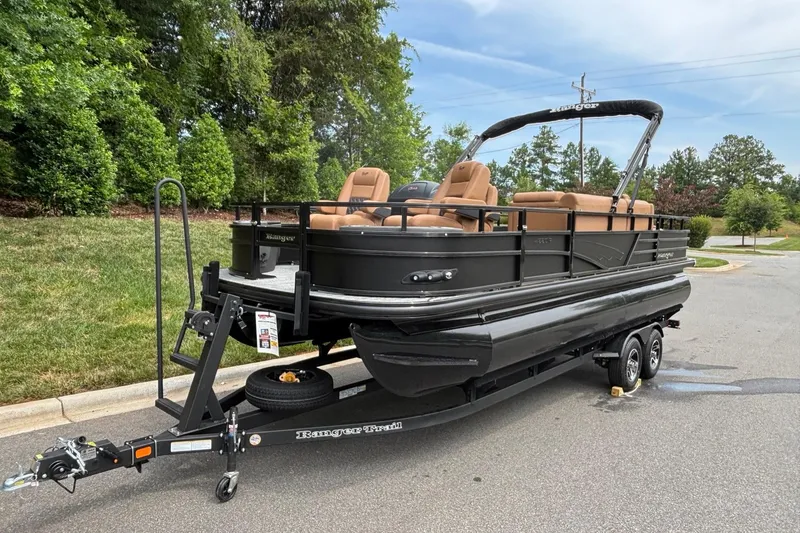 Slide: The Image of 2026 Ranger 220F pontoon boat on trailer, parked on a road near greenery. - 2