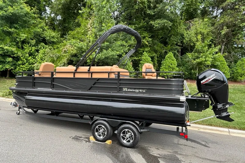Slide: The Image of 2026 Ranger 220F pontoon boat with Mercury engine on trailer, surrounded by lush greenery. - 3