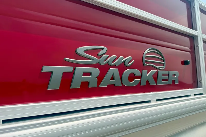 Slide: The Image of Close-up of 2026 Sun Tracker Party Barge 18 DLX logo on red background. - 29