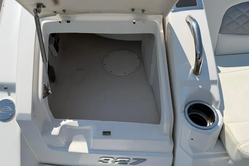 Slide: The Image of Open storage compartment on 2012 Chaparral 327 SSX boat, featuring cup holder and handle. - 11