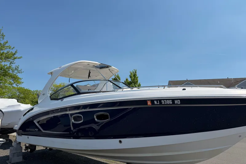 Slide: The Image of 2012 Chaparral 327 SSX boat with sleek design, parked outdoors under clear blue sky. - 2