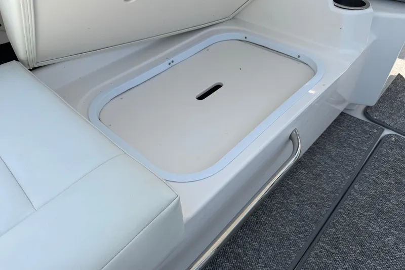 Slide: The Image of 2012 Chaparral 327 SSX boat storage compartment with cushioned seating and metal handle. - 21