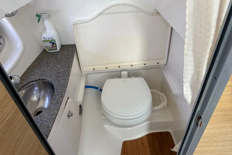 Slide: The Image of 2012 Chaparral 327 SSX boat bathroom with sink, toilet, and cleaning supplies. - 38