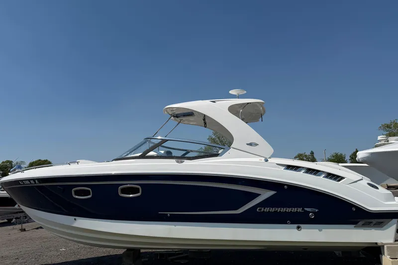Slide: The Image of 2012 Chaparral 327 SSX boat with sleek design, docked under clear blue sky. - 5