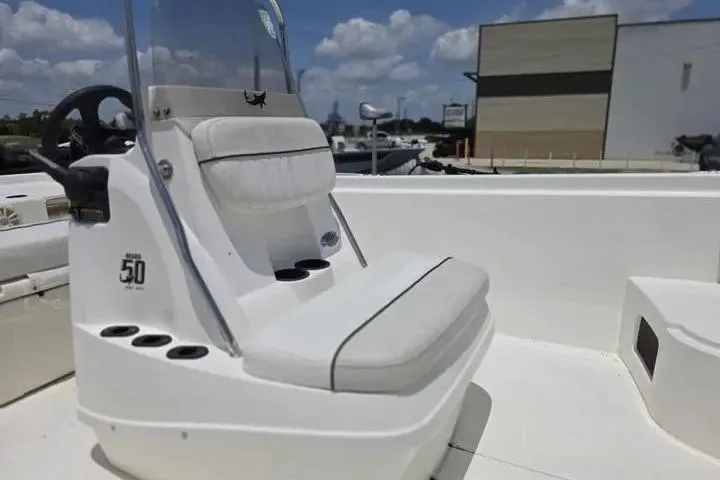 Slide: The Image of 2017 Mako Pro Skiff 21 CC boat interior with seating and console, under a clear blue sky. - 11