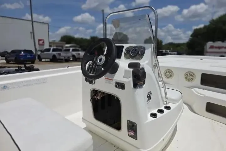 Slide: The Image of 2017 Mako Pro Skiff 21 CC boat console with steering wheel and gauges under a sunny sky. - 13
