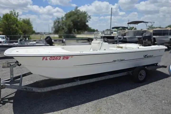 Slide: The Image of 2017 Mako Pro Skiff 21 CC boat on trailer, parked outdoors under a cloudy sky. - 2
