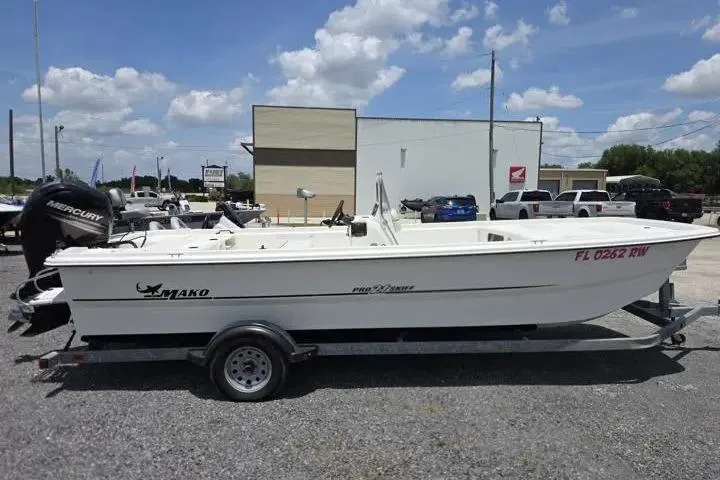 Slide: The Image of 2017 Mako Pro Skiff 21 CC boat on trailer, parked outdoors under a cloudy sky. - 6