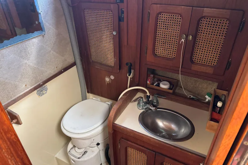 Slide: The Image of Compact 1981 S2 36 sailboat bathroom with wooden cabinets, sink, and marine toilet. - 13