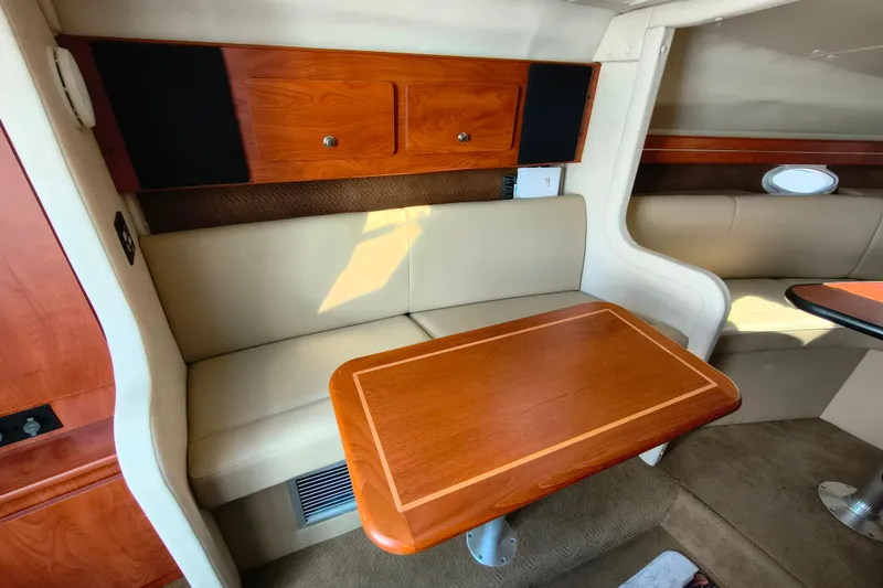 Slide: The Image of Interior of 2006 Rinker 300 Express Cruiser with wood table and beige seating. - 16