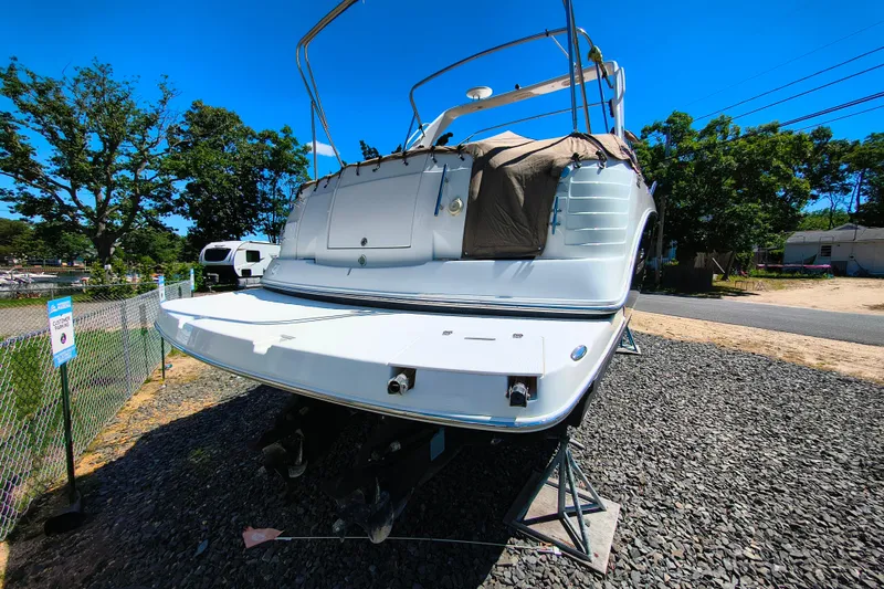 Slide: The Image of 2006 Rinker 300 Express Cruiser on stands, outdoors, under clear blue sky. - 23