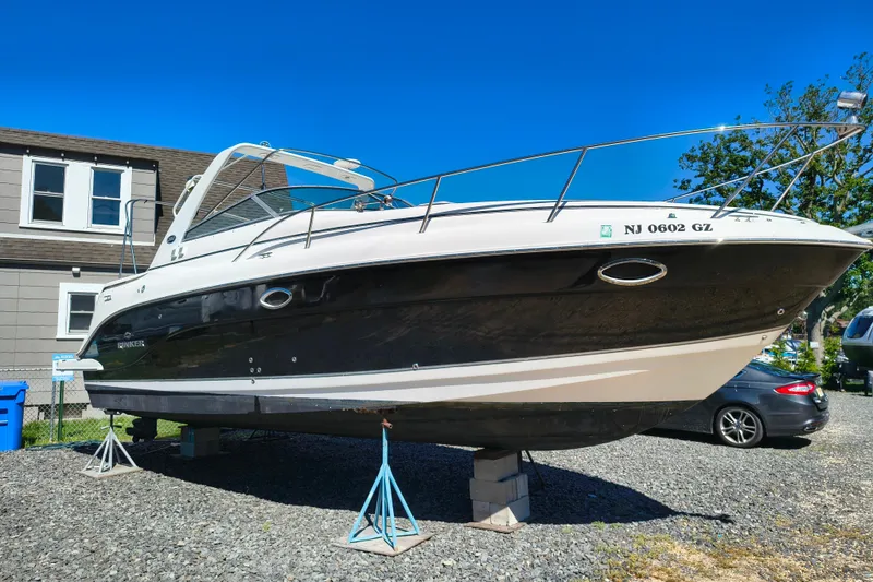 The Image of 2006 Rinker 300 Express Cruiser on stands, parked outdoors under clear blue sky. - 4