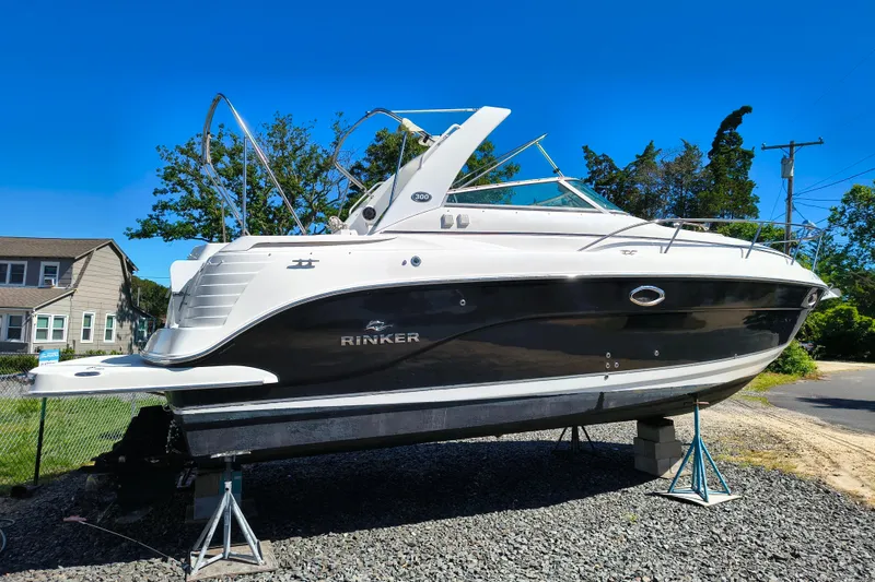 Slide: The Image of 2006 Rinker 300 Express Cruiser boat on stands, outdoors, under clear blue sky. - 5