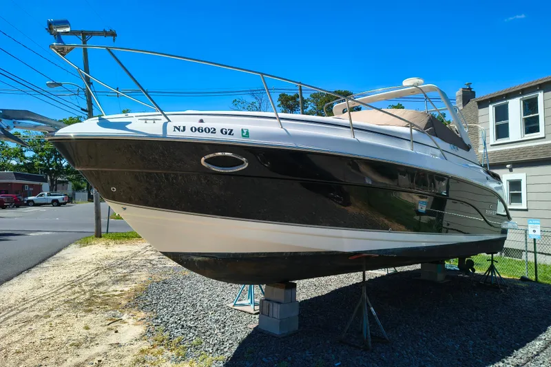 Slide: The Image of 2006 Rinker 300 Express Cruiser on blocks, parked outdoors under clear blue sky. - 6