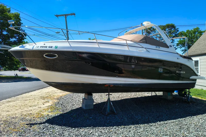 Slide: The Image of 2006 Rinker 300 Express Cruiser boat on stands, parked outdoors on gravel. - 7