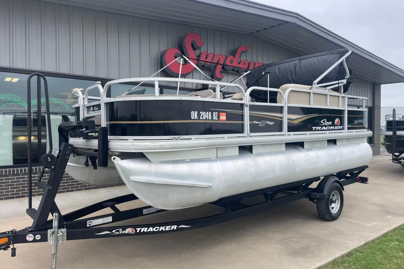 Slide: The Image of 2021 Sun Tracker Bass Buggy 18 DLX pontoon boat on trailer outside dealership. - 2