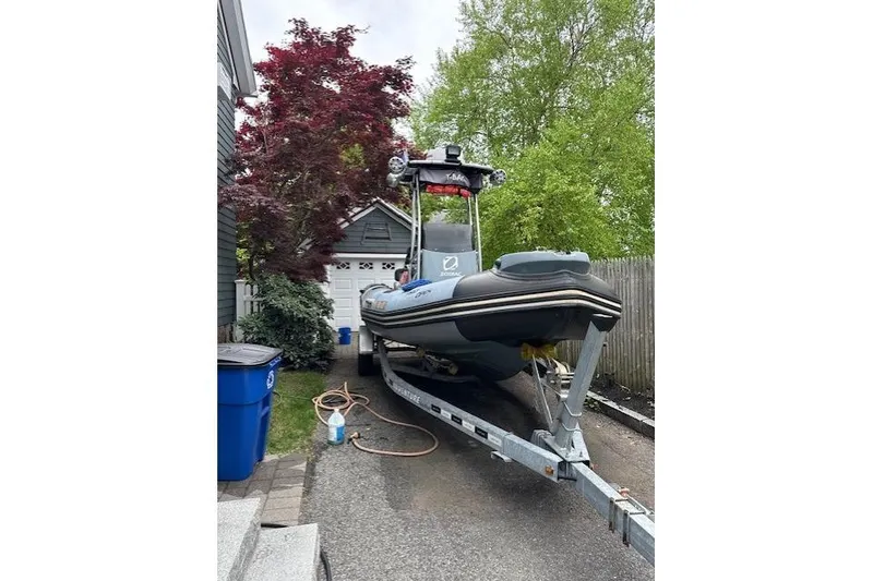 Slide: The Image of 2018 Zodiac Pro Open 650 boat on trailer in driveway, surrounded by trees. - 6