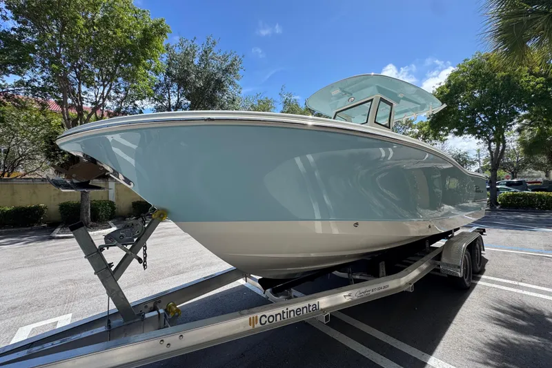 Slide: The Image of 2026 Pioneer 250 Pelagic boat on trailer, parked outdoors under clear blue sky. - 2