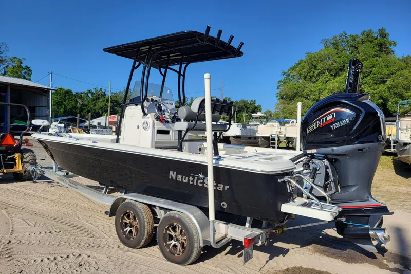 Slide: The Image of 2023 NauticStar 227 XTS boat with Yamaha engine on trailer, parked outdoors. - 2