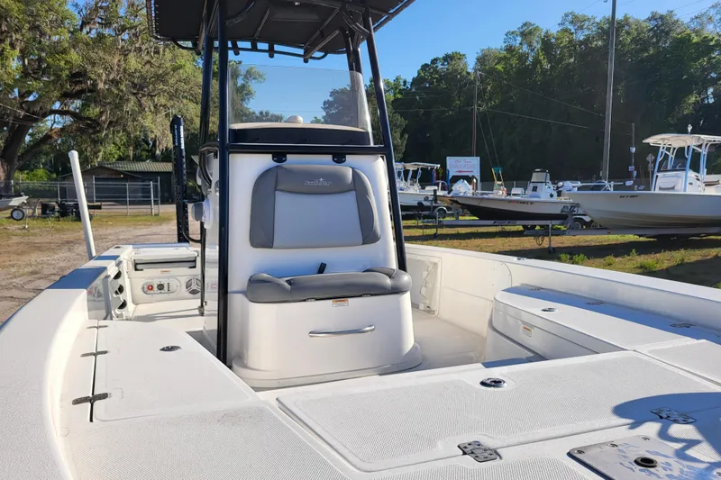 Slide: The Image of 2023 NauticStar 227 XTS boat interior with seating and console, parked outdoors. - 4
