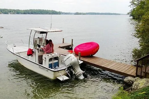 Slide: The Image of 1993 Maritime Skiff 2090cc docked by a lake with a red inflatable tube. - 2