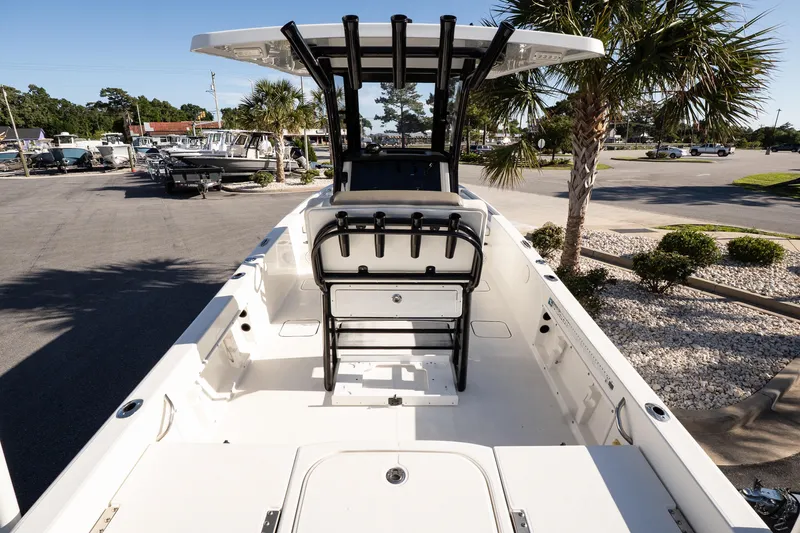 Slide: The Image of 2023 World Cat 235 CC boat interior with seating and T-top, parked near palm trees. - 8