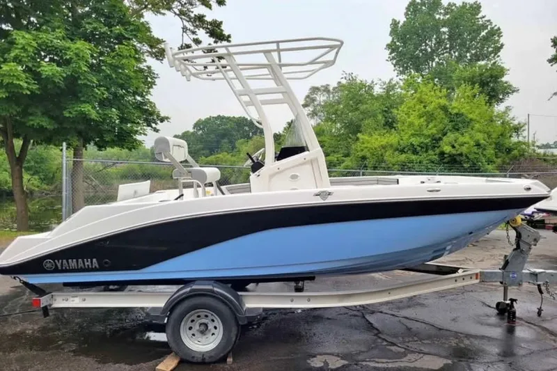 Slide: The Image of 2024 Yamaha Boats 190 FSH Sport on trailer, parked outdoors near trees. - 11