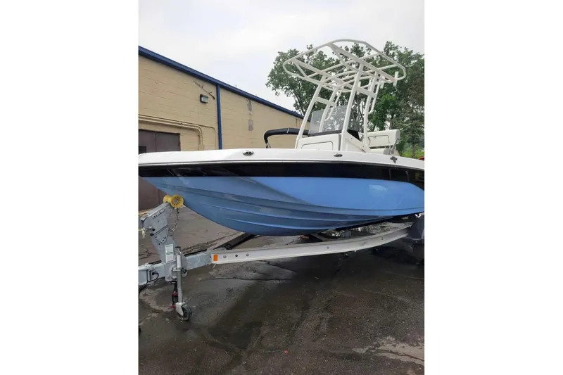 Slide: The Image of 2024 Yamaha Boats 190 FSH Sport in blue, parked on a trailer outside a building. - 2